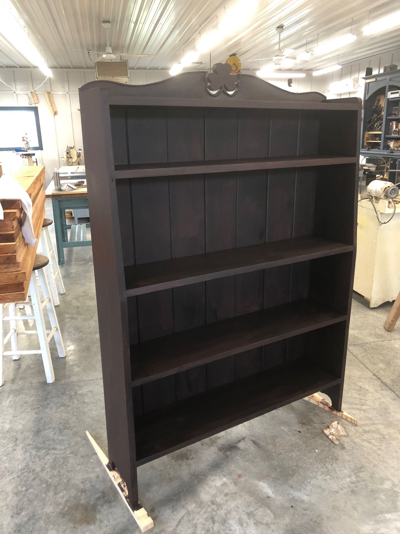 Dark-stained pine bookcase with a shamrock pierced through the crest rail